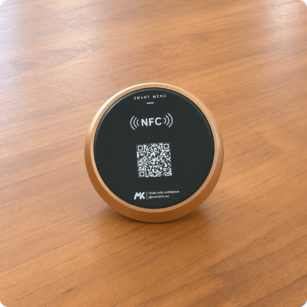 A round Menukits NFC card with a QR code on a wooden table.